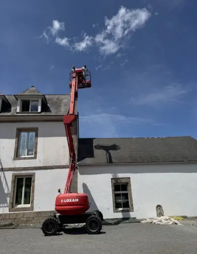 Volunteers on a boom lift painting the exterior of a stone-trimmed building in France for PDV France